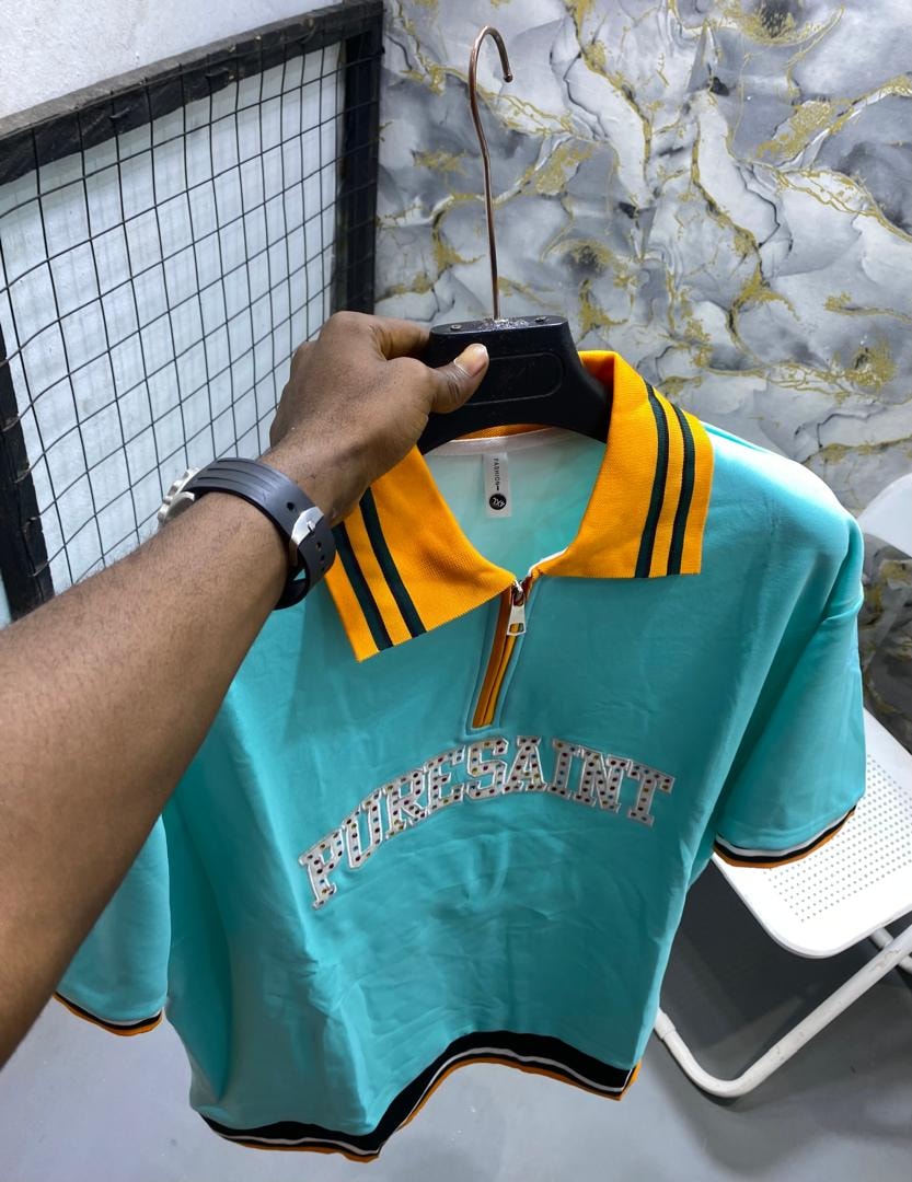 Teal short-sleeve polo shirt with yellow collar, green stripes and PURESAINT graphic on chest.