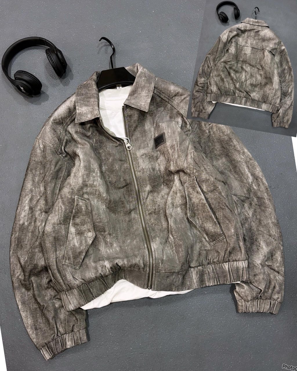 Gray distressed bomber jacket on black hanger with headphones and back view inset.