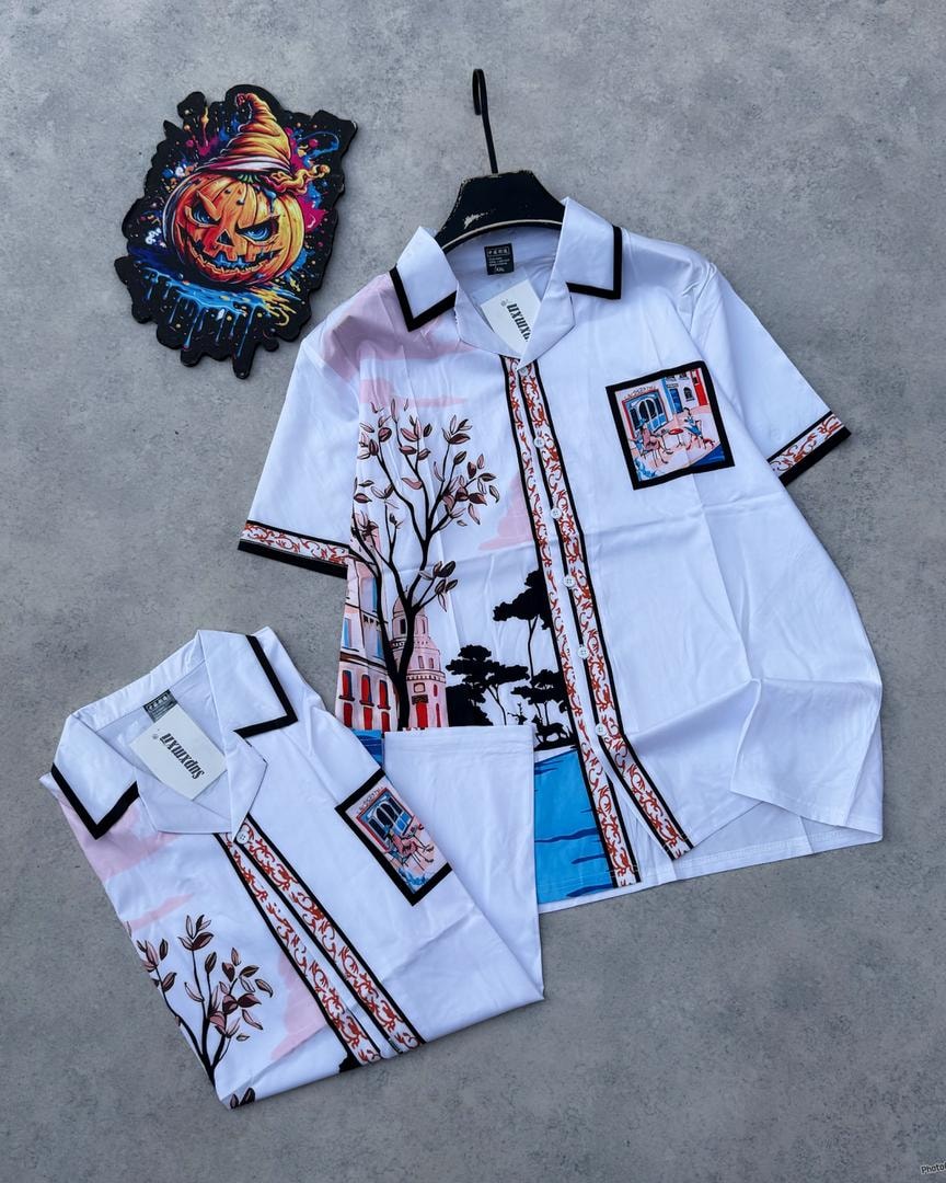 White short sleeve shirt with colorful building and tree illustrations, black trim on collar.