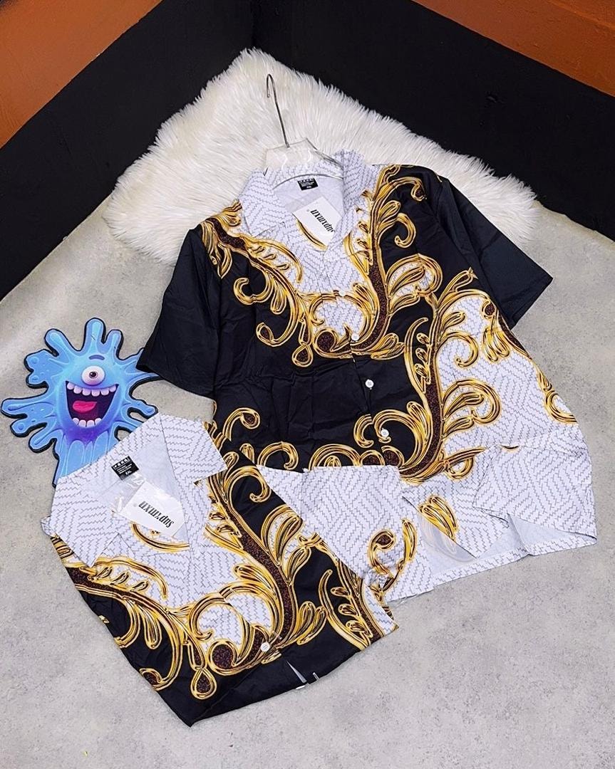 Black short sleeve shirt with gold and white ornate baroque pattern on hanger and flat.