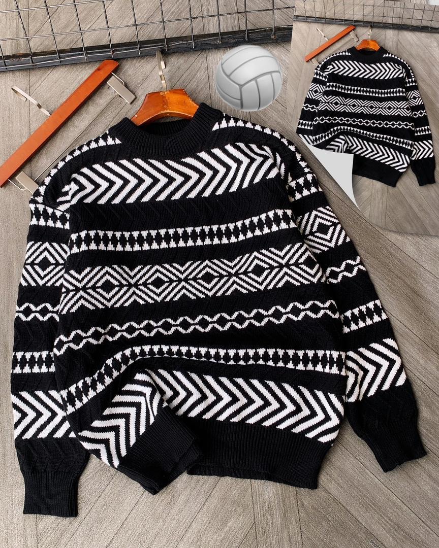 Black geometric patterned knitted sweater on wooden hanger with volleyball and clips.