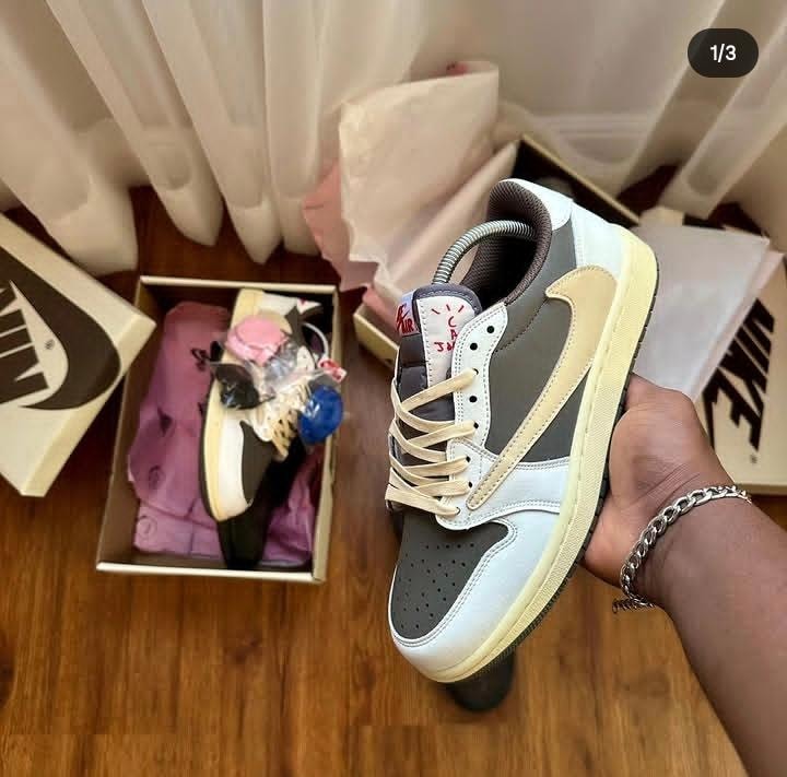 Gray white and beige Nike Jordan 1 Low held in hand with Nike boxes.