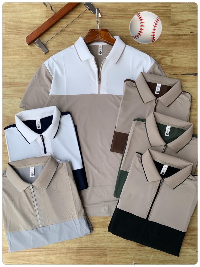 Assorted colorblock zip polo shirts in various two-tone designs displayed on wooden floor with props.