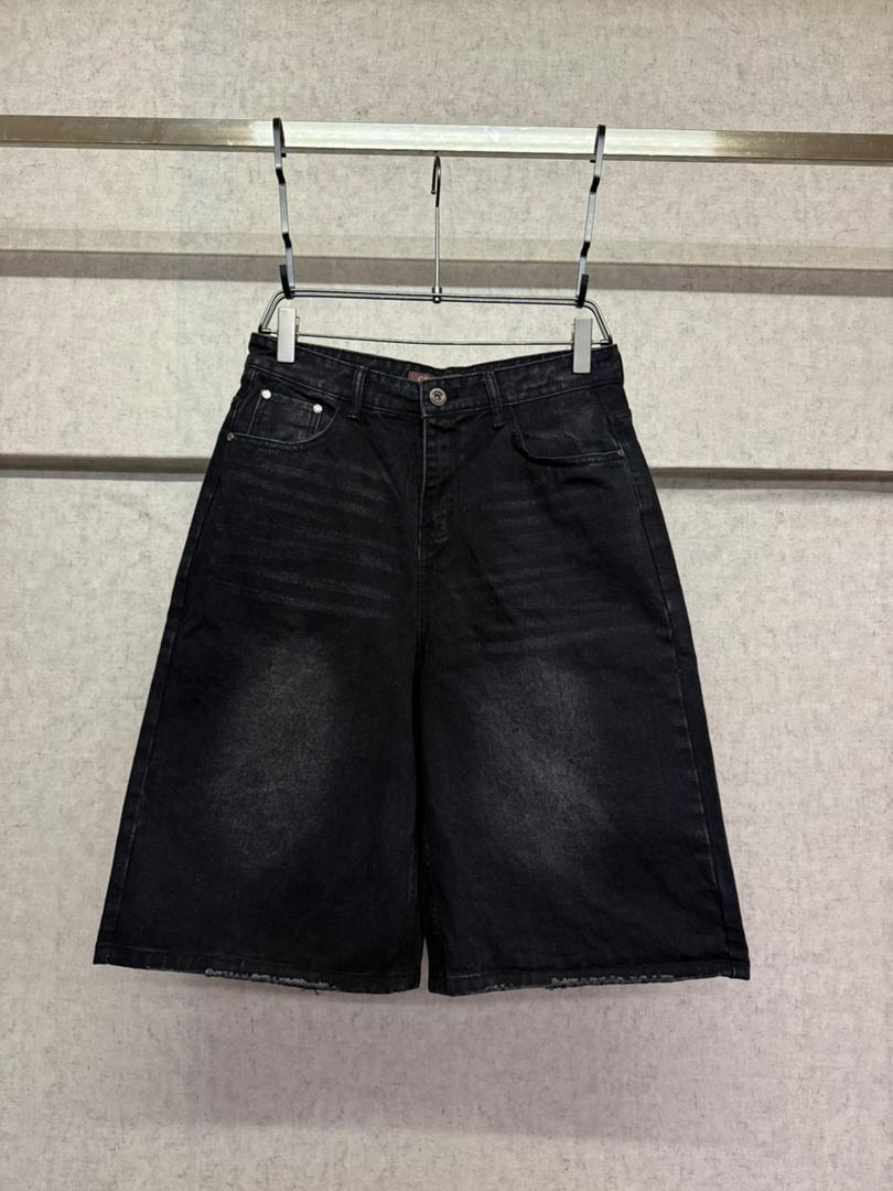 Black faded 3/4 denim shorts hanging on a metal rack, front view showing distressing.