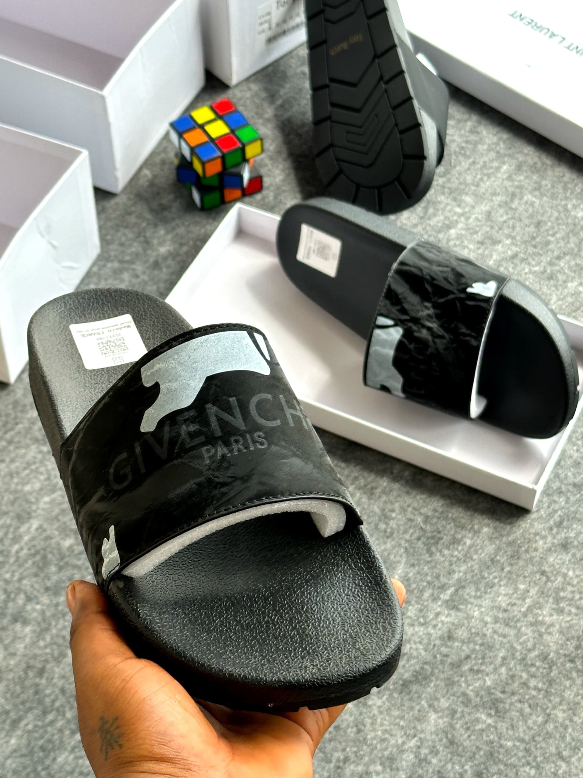 Black camo pattern slide with GIVENCHY PARIS text, held showing the design details and background elements.