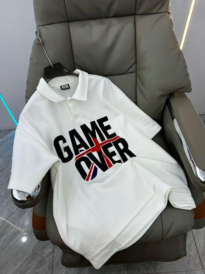 White GAME OVER polo shirt displayed on a chair.