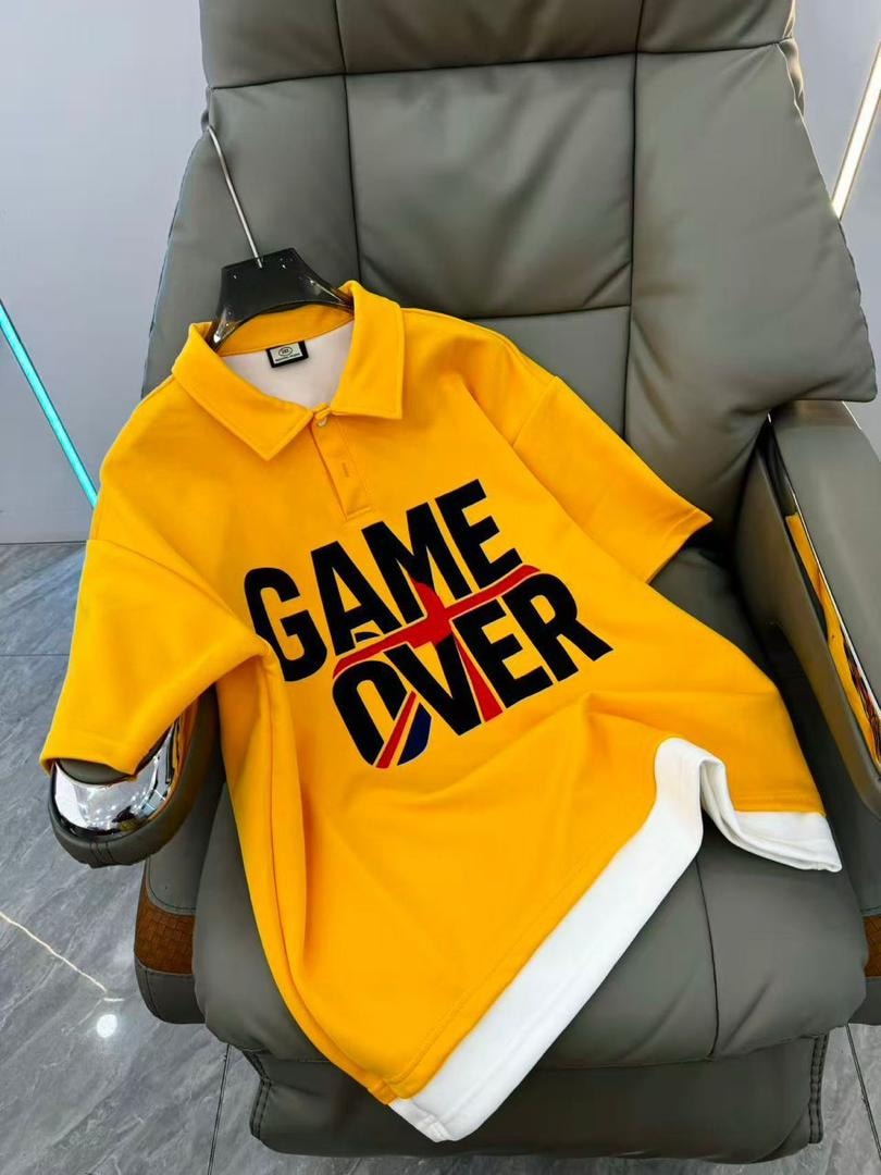 Yellow GAME OVER polo shirt displayed on a chair.