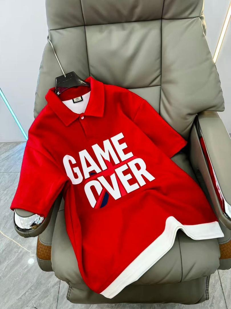 Red GAME OVER polo shirt displayed on a chair.