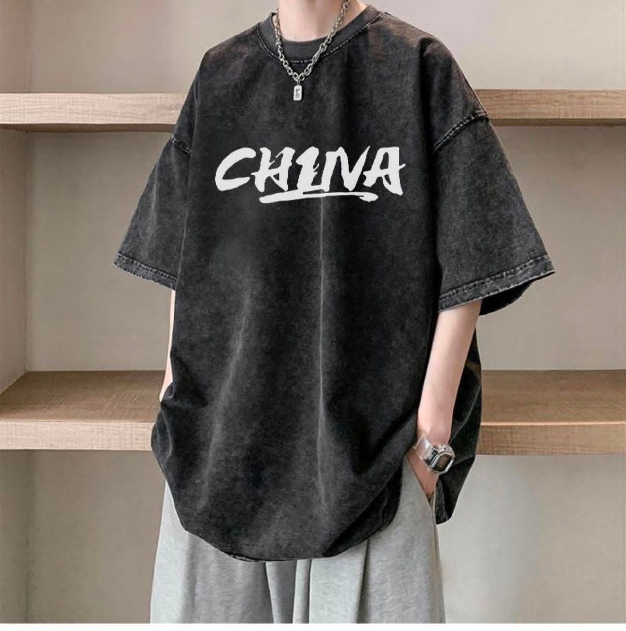 Person wearing dark washed oversized t-shirt with white CHINA text print.