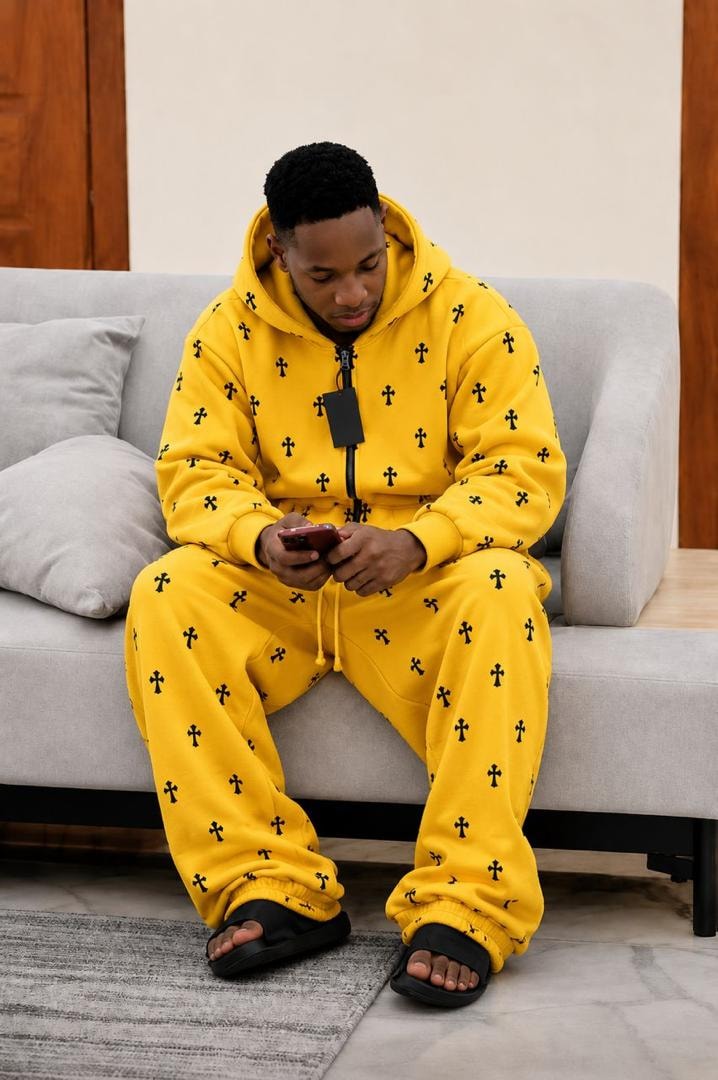 Model wearing yellow cross print zip-up two-piece hoodie and pants set.