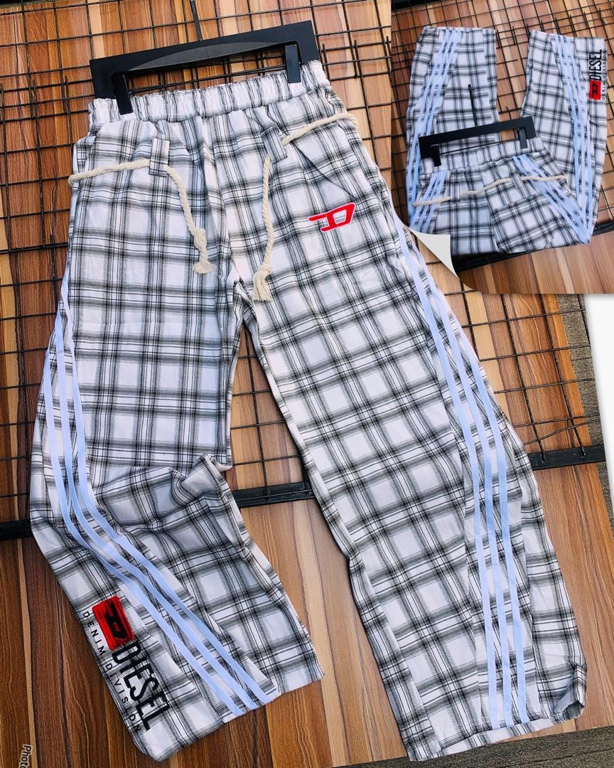 Diesel white plaid joggers with blue stripes and red logo detail on wooden floor.