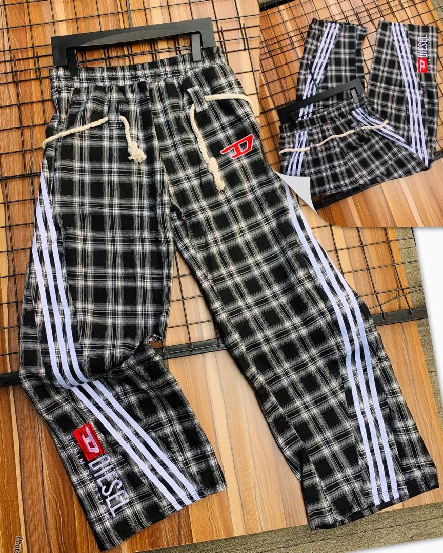 Diesel black and white plaid joggers on hanger showing full front with white side stripes and red logo.
