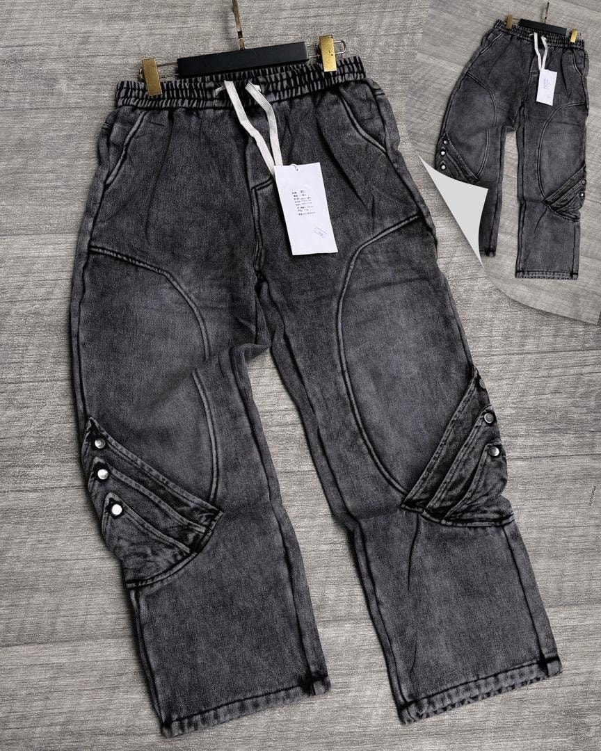 Gray panelled denim joggers with knee patches, stitched seams and side buttons.