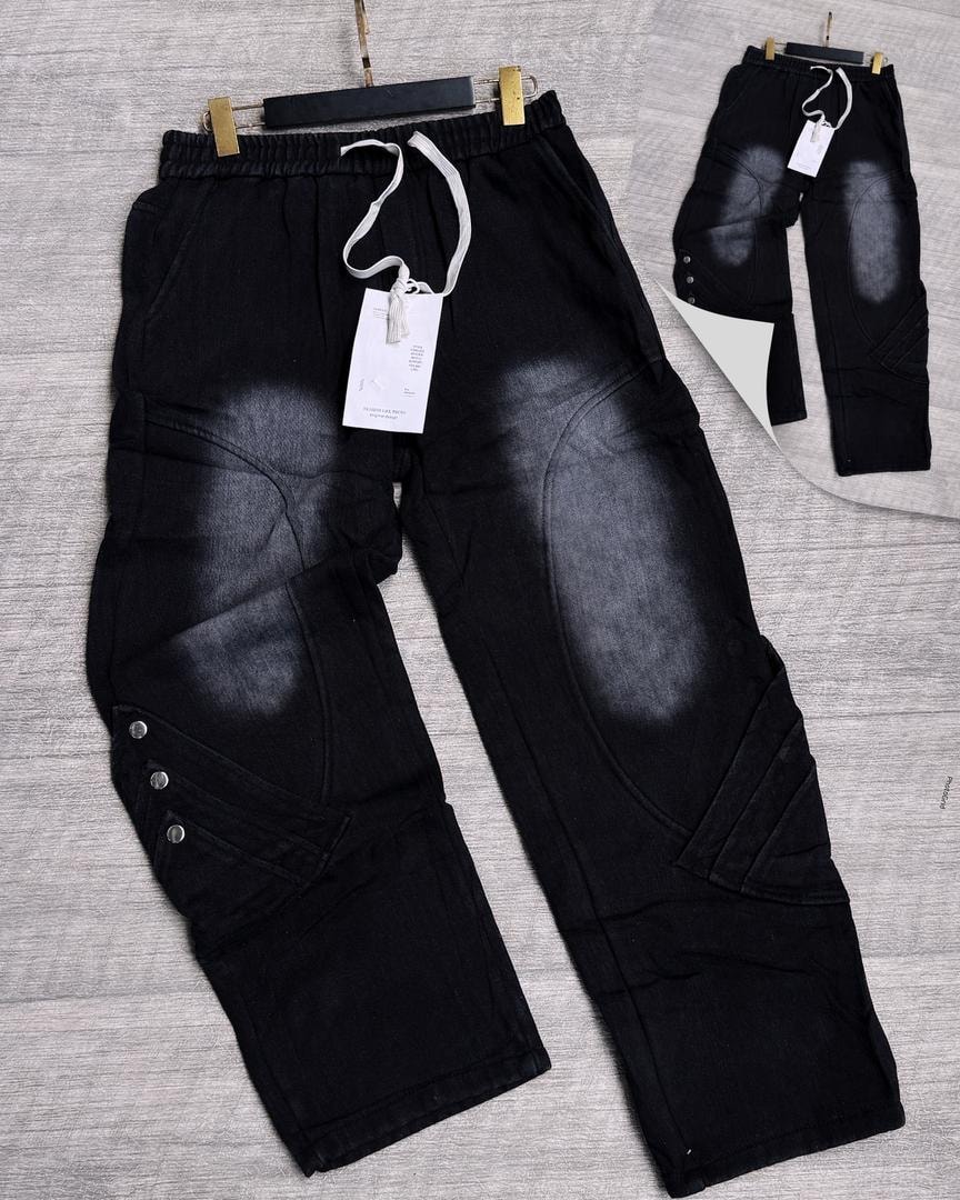 Black panelled denim joggers with knee patches, stitched seams and side buttons.