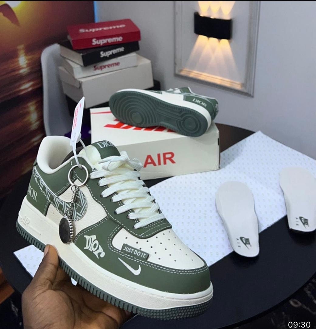 Green and white Nike Air Force 1 Low sneakers with Dior logos, keychain, and accessories on display.