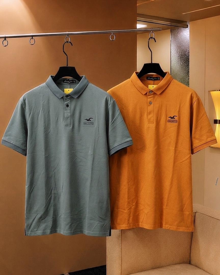 Light blue and orange Hollister polo shirts hanging side by side.