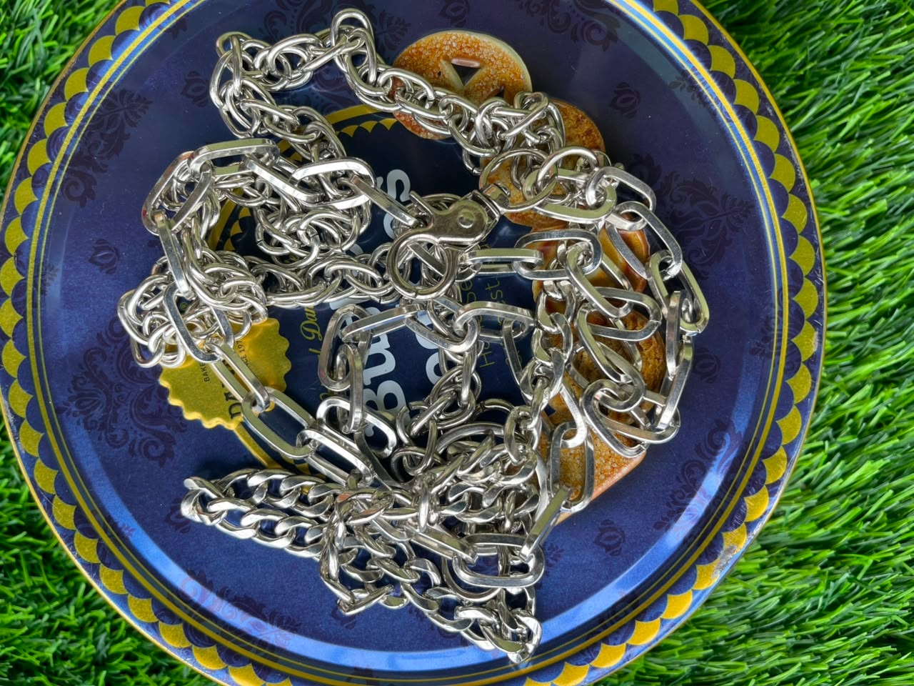 Thick silver link jean chain with lobster clasp on decorative blue plate.
