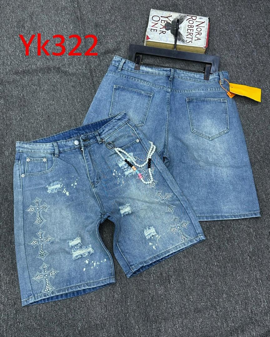Flat lay of front and back of distressed blue denim jorts showing cross motifs, distressing, and beaded chain.