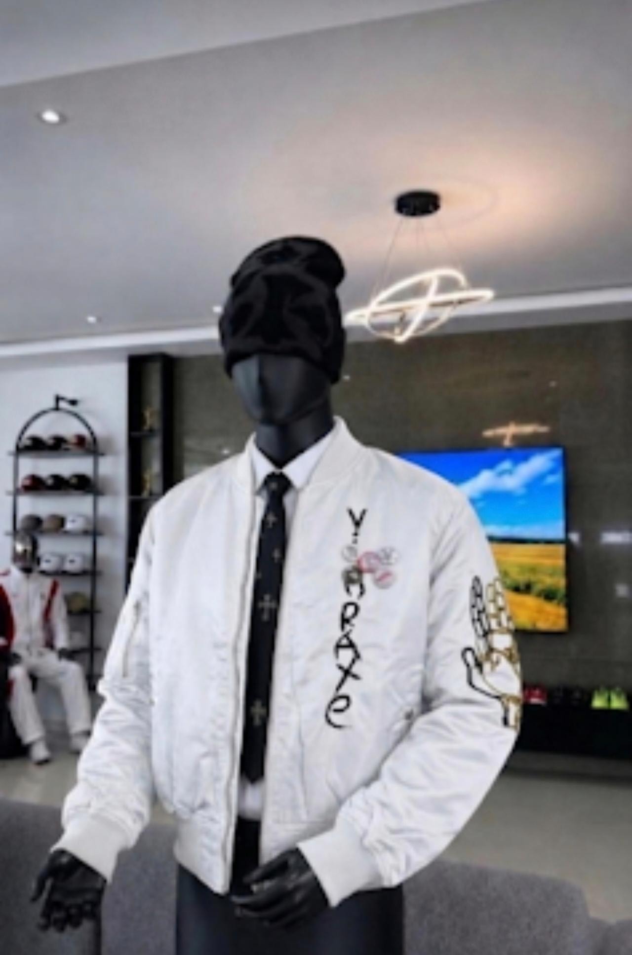 White unisex bomber jacket with YORAXE chest embroidery and praying hands sleeve graphic on mannequin.