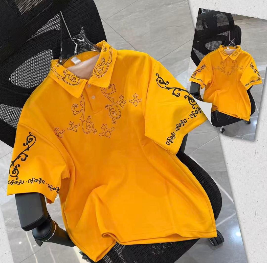 Yellow polo shirt with black ornate embroidery on chest, sleeves and collar.