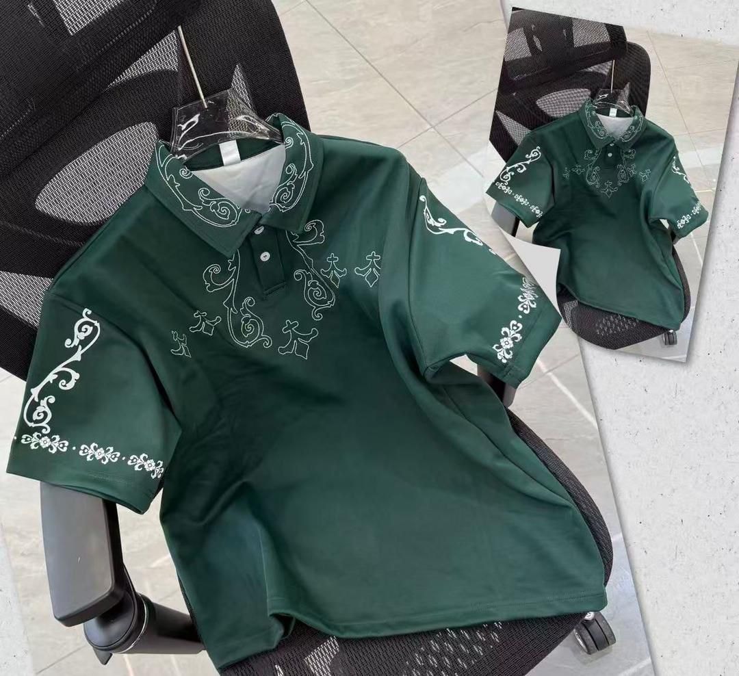 Green polo shirt with white ornate embroidery on chest, sleeves and collar.