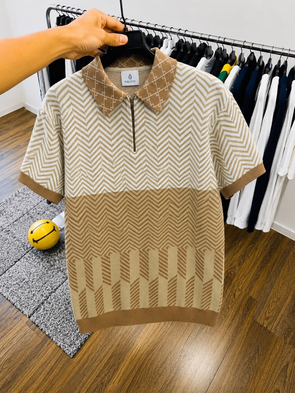 Beige chevron knit polo shirt displayed on hanger.
