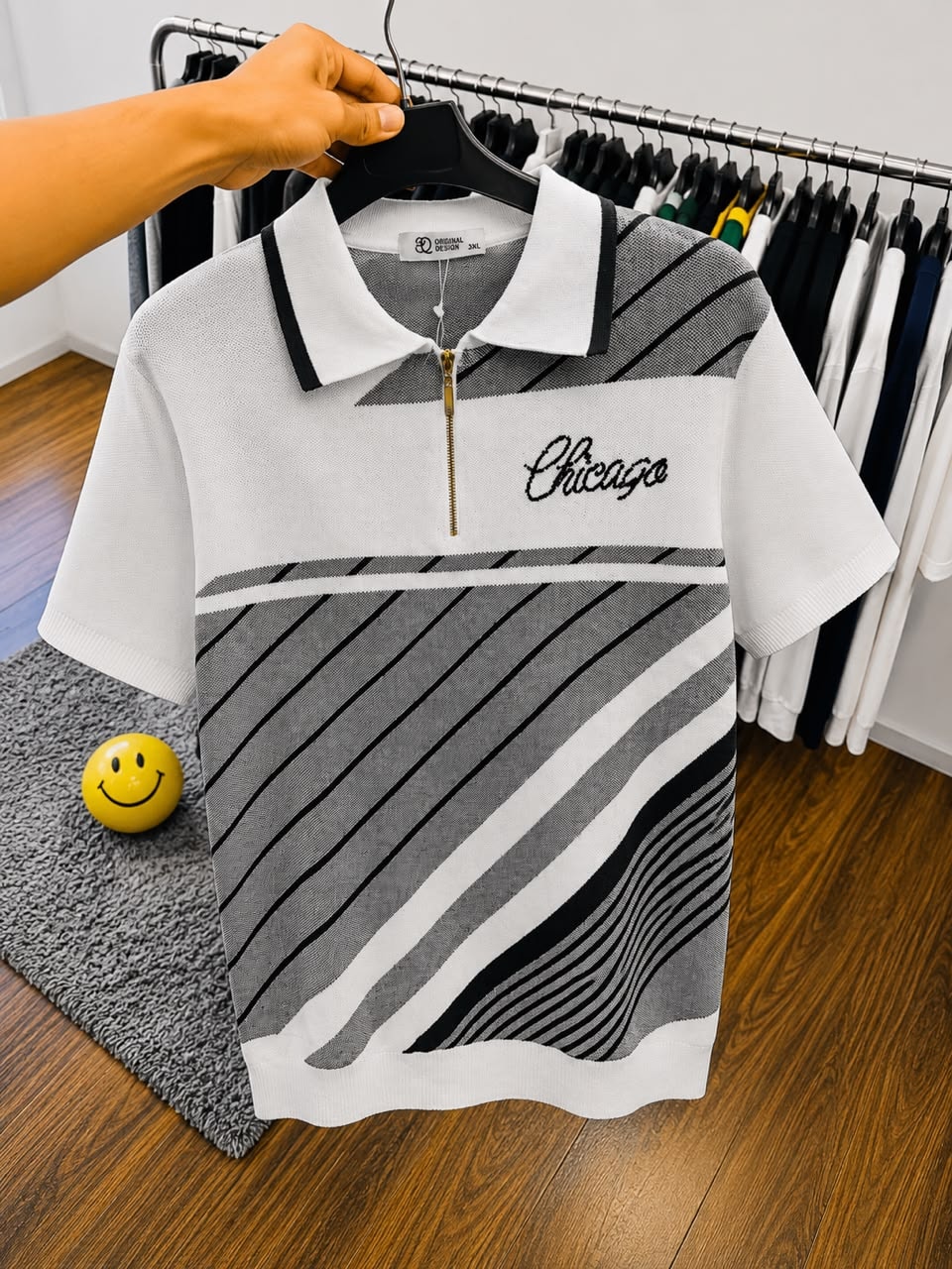 White Chicago polo shirt with gray and black stripes on hanger.