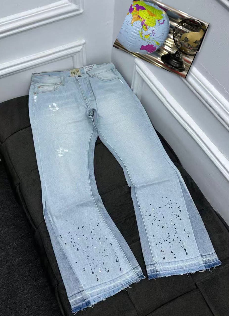Light blue baggy jeans laid flat showing paint splatter details on legs, raw hem and Gallery Dept tag.