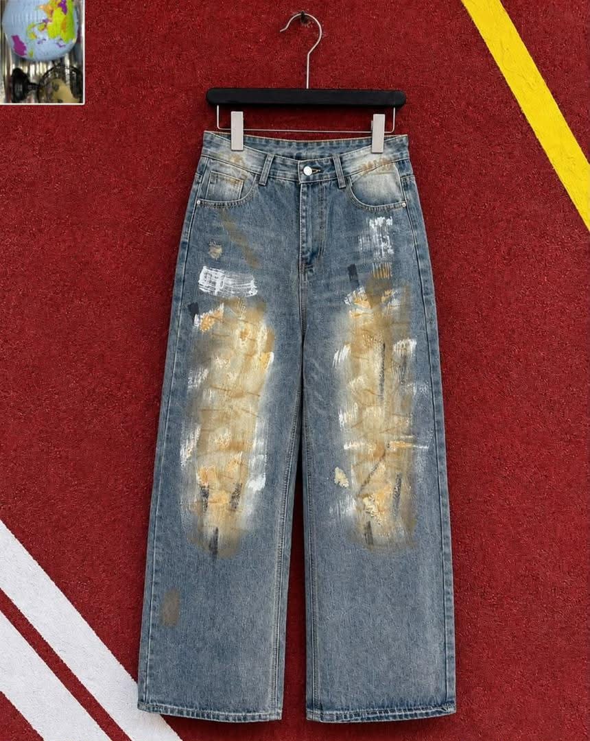 Blue baggy jeans with yellow and white paint strokes hanging against red background.