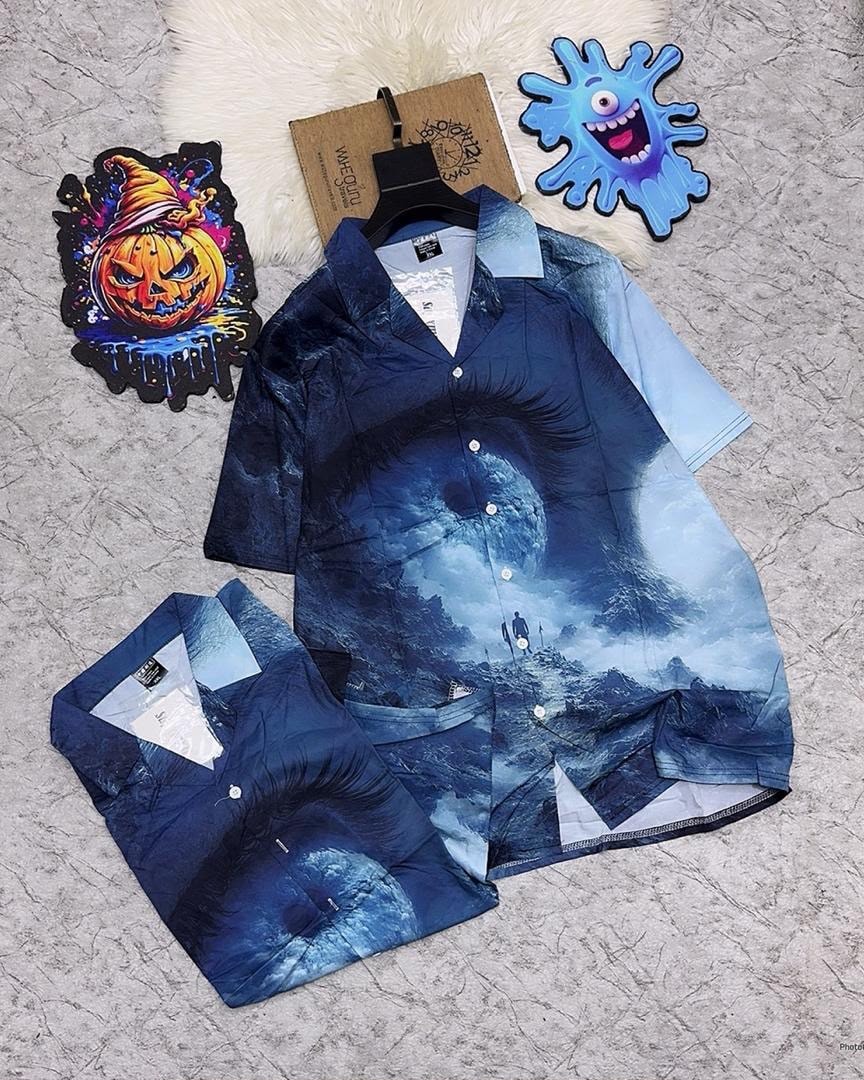 Blue short sleeve shirt with eye, moon, and mountain landscape print.