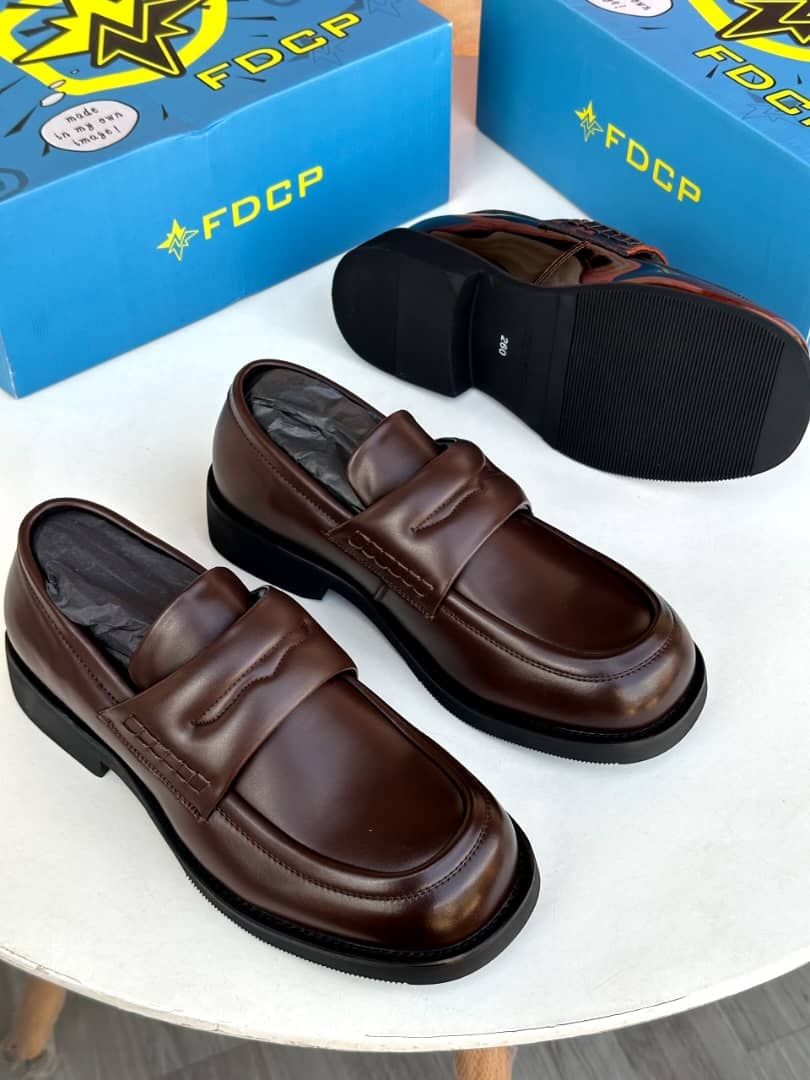 Brown loafers displayed on white table with FDCP blue boxes.