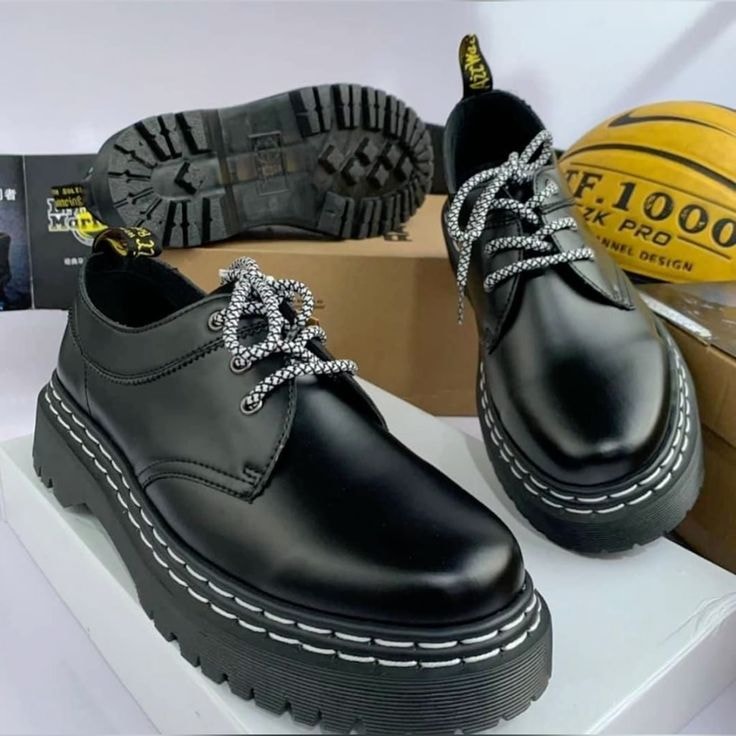 Black platform derby shoes with white stitching and patterned laces, sole view visible.