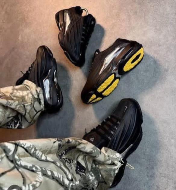 Black chunky sneakers with yellow soles worn with camo pants, multiple angles shown.