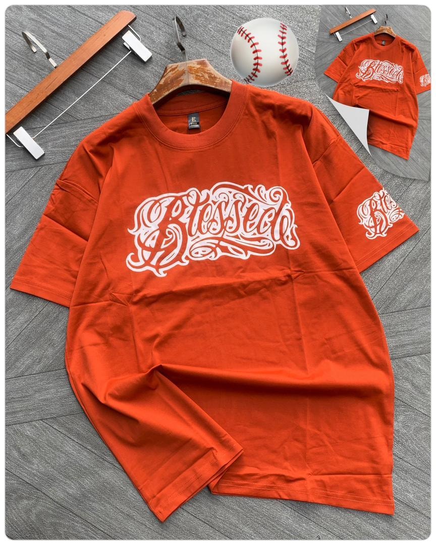 Orange tee with white Blessed calligraphy on chest and sleeve.