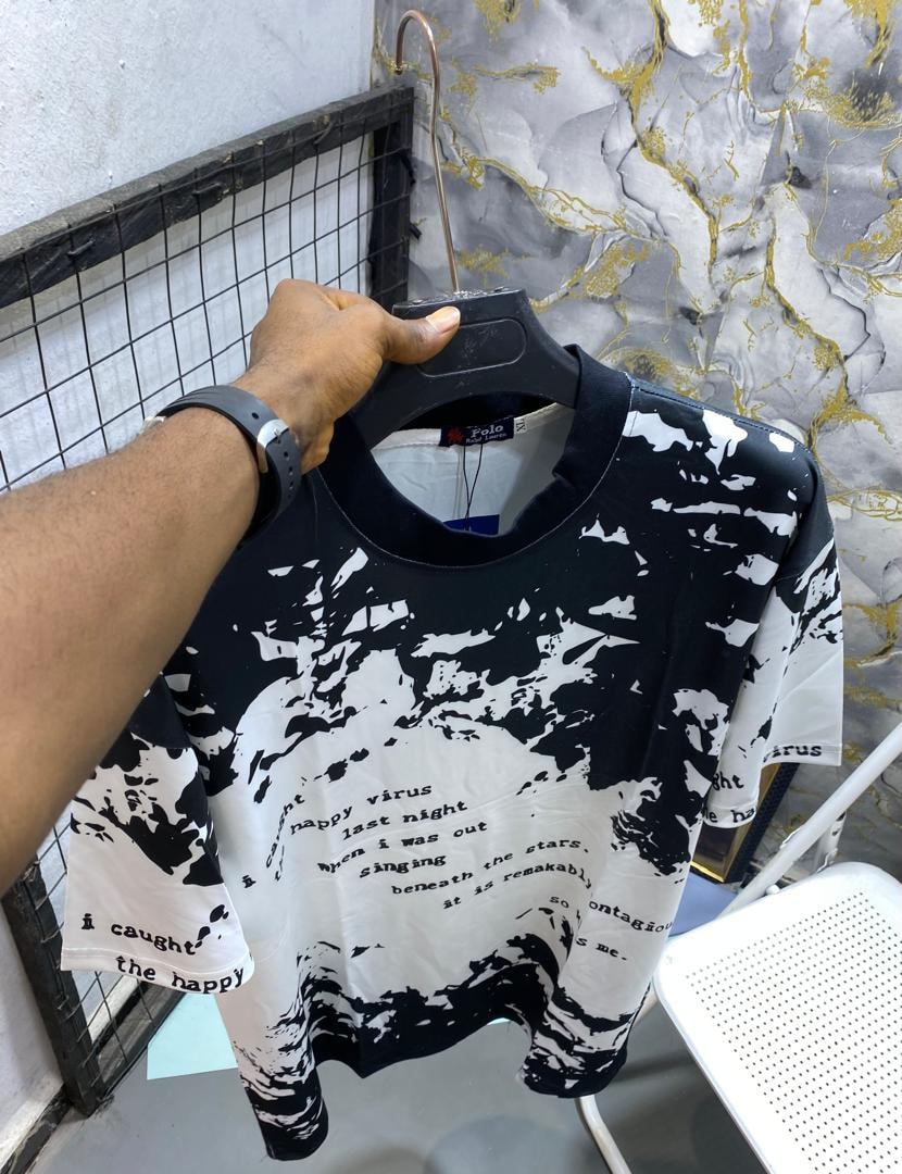 Black and white splash print t-shirt held on a hanger showing text details.
