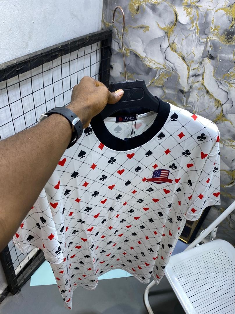 White playing cards pattern t-shirt held up on a black hanger.