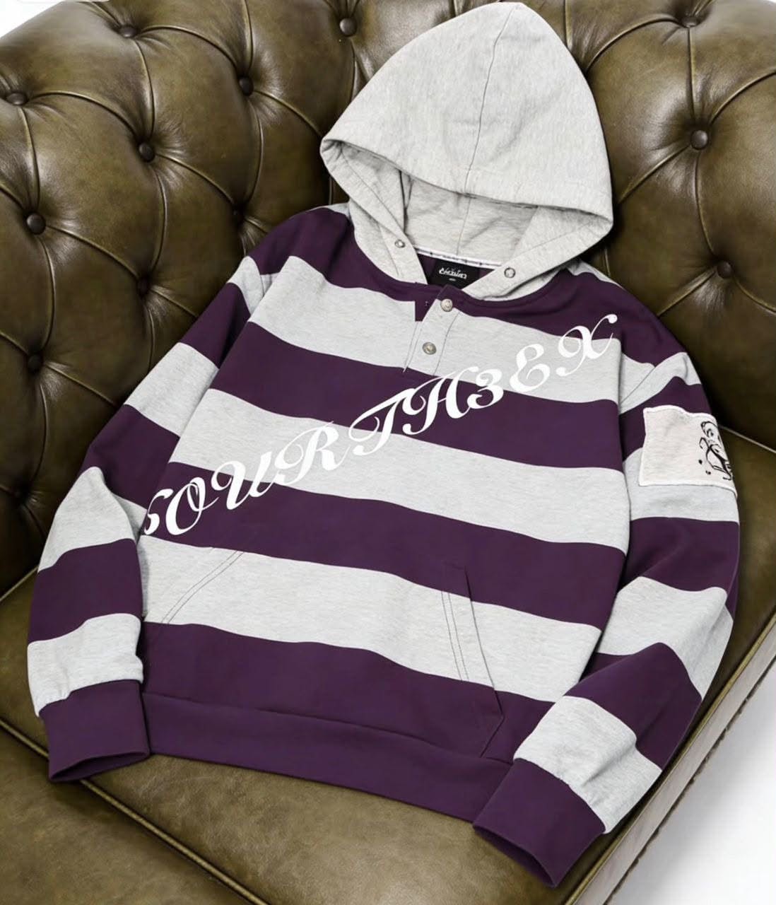 Purple striped hoodie laid flat on brown leather couch.