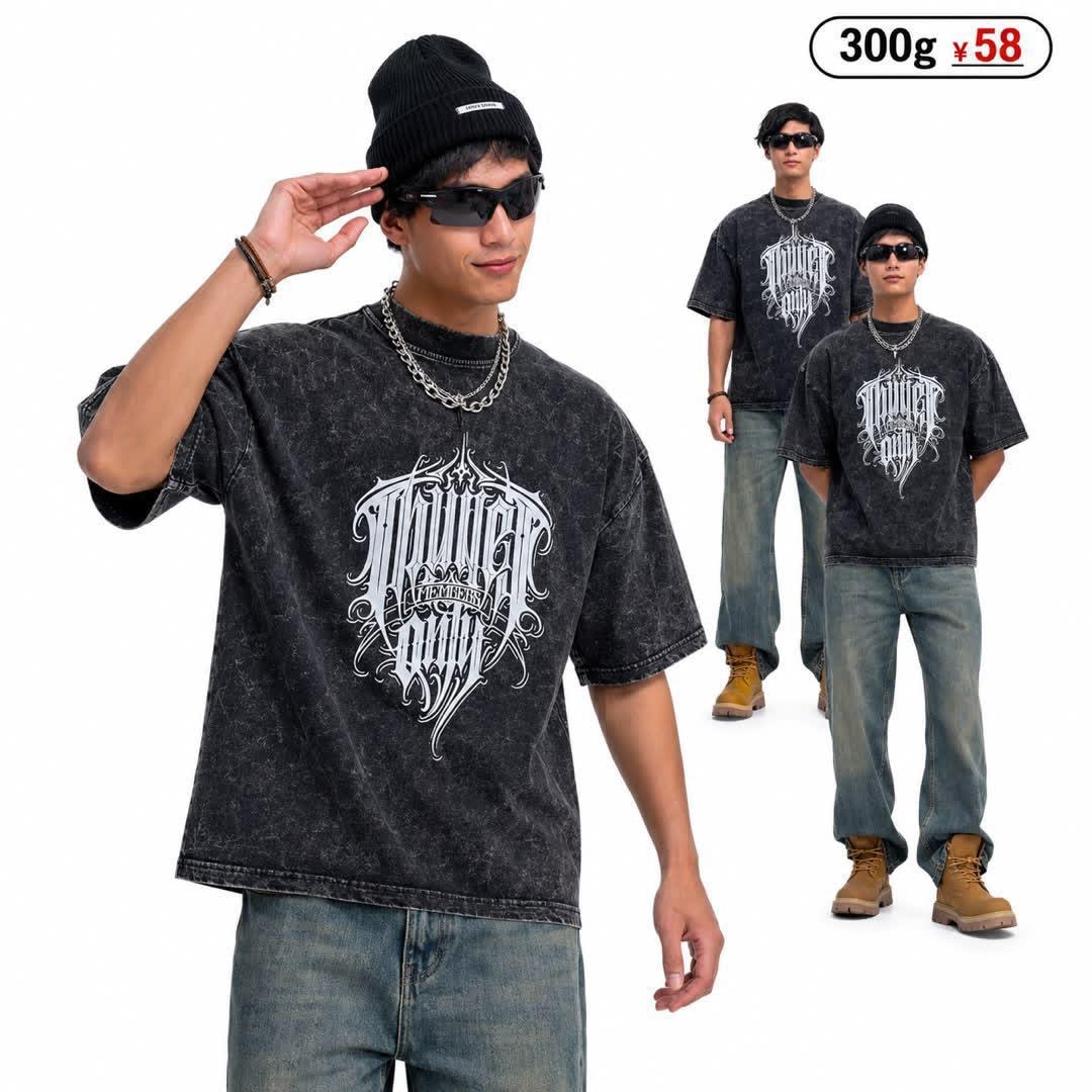 Man modeling black stonewash t-shirt with large white ornate graphic print on chest.