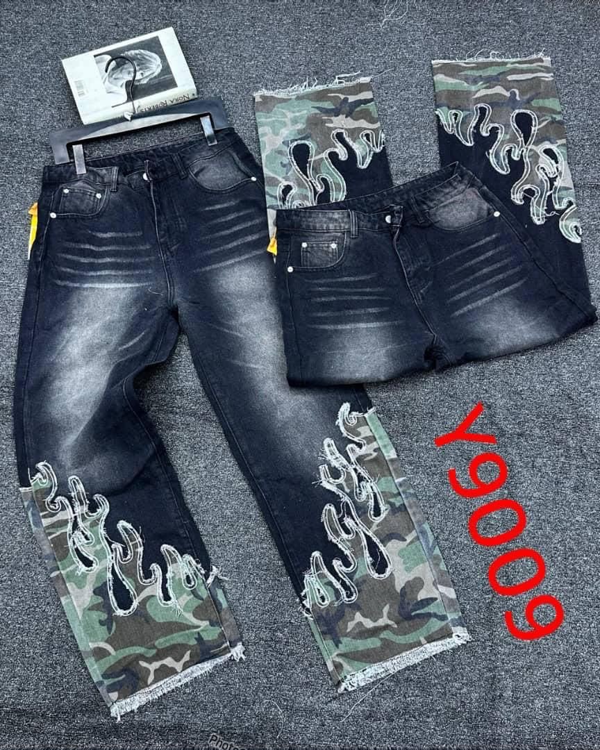 Black baggy jeans with camo lower legs and white flame embroidery in flat lay views.