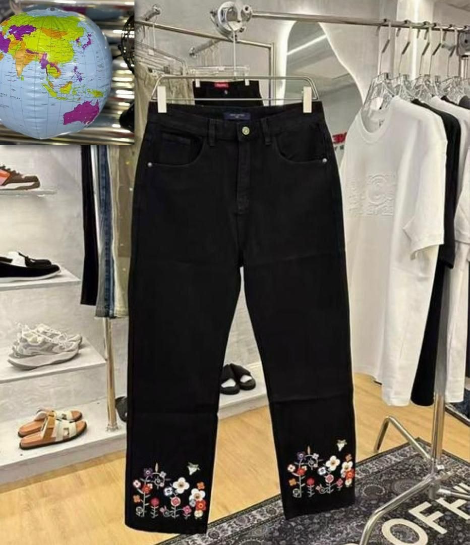 Black jeans with colorful floral embroidery on cuffs hanging in store.