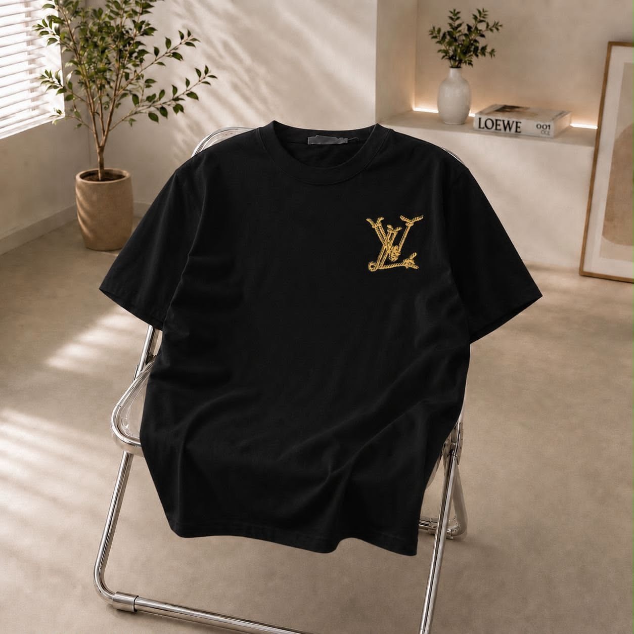 Black t-shirt with gold LV embroidered logo on chest.