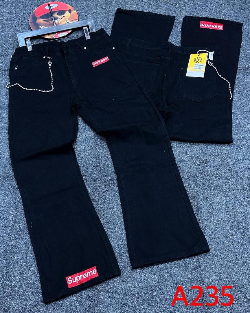 Black Supreme baggy jeans with red logos and chain detail laid flat with folded back view.