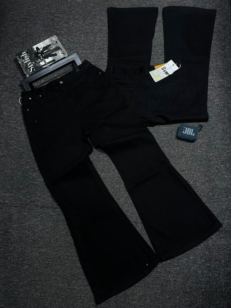 Flat lay of black baggy flare jeans with front, back and accessory props.