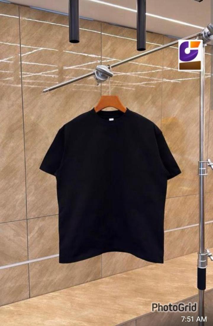 Black plain unisex crew neck t-shirt on wooden hanger against tiled background.
