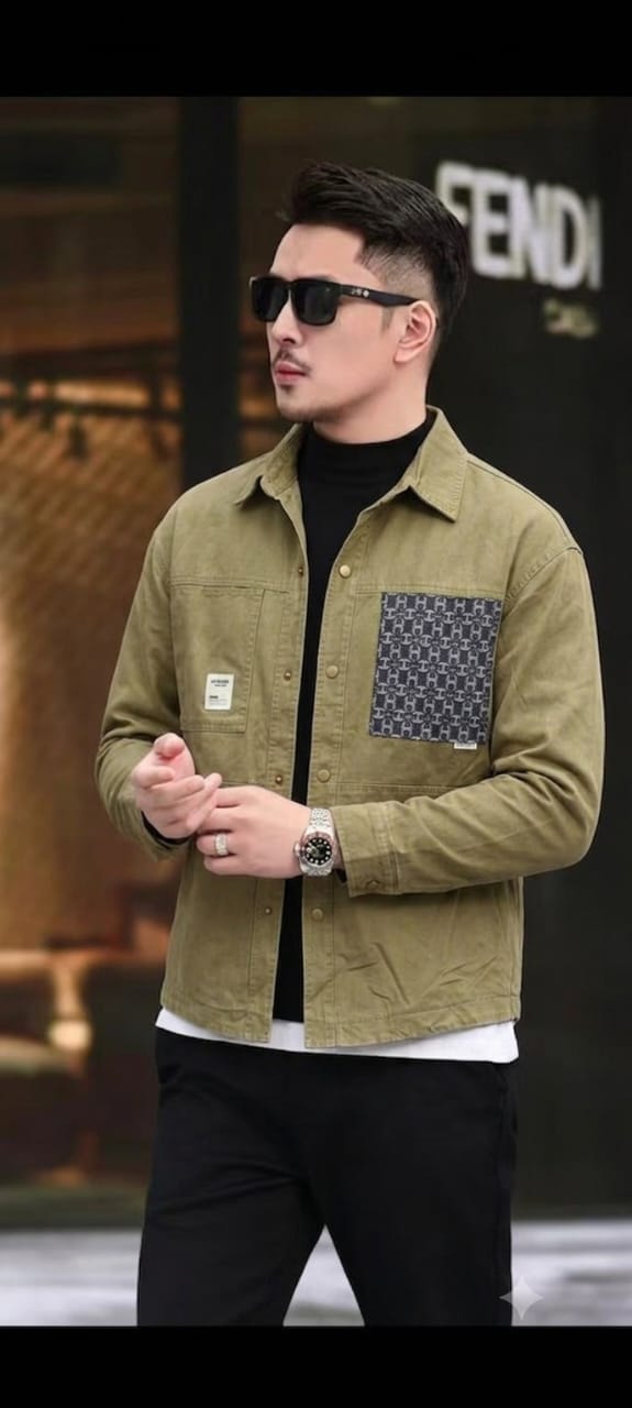 Model wearing Omeg olive long-sleeve button-down shirt with patterned chest pocket, layered over black turtleneck.