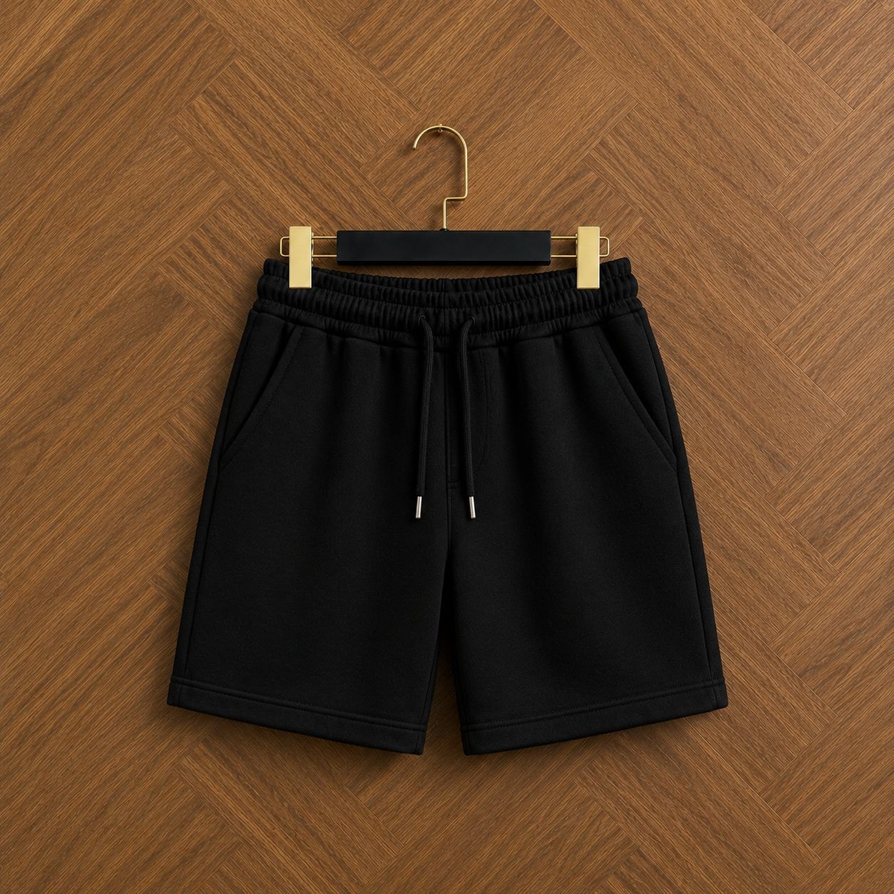 Black unisex fleece shorts front view hanging on wooden floor.