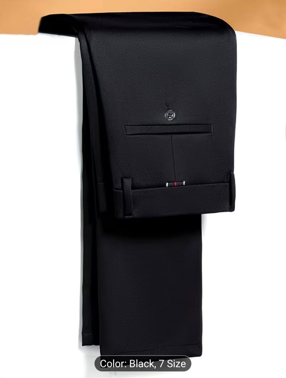 Folded black trousers close-up showing back pocket, button and tab detail on white background.