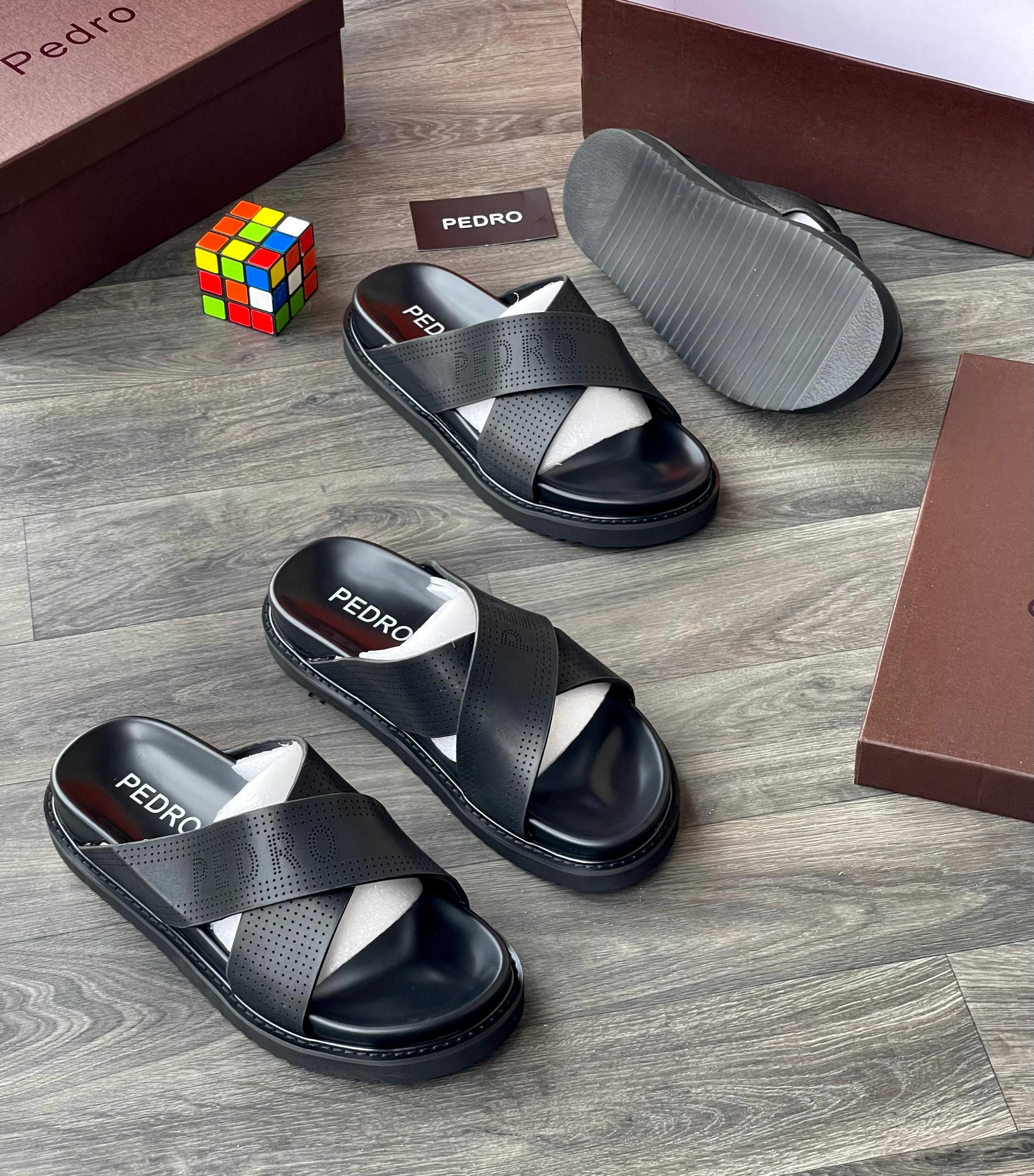 Black Pedro perforated slides displayed with brown boxes, card and Rubik's cube.