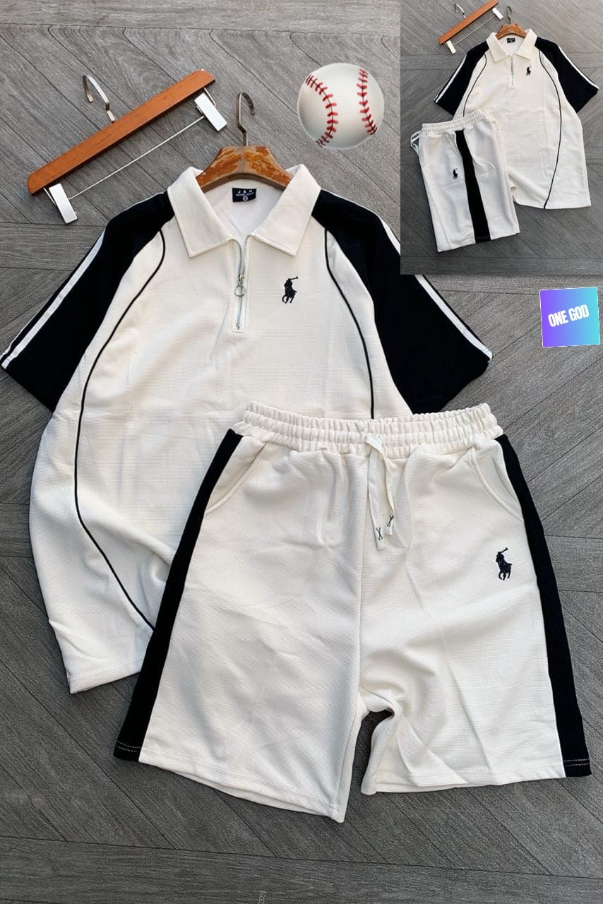 White polo two-piece set with black contrast sleeves and shorts laid out with accessories.