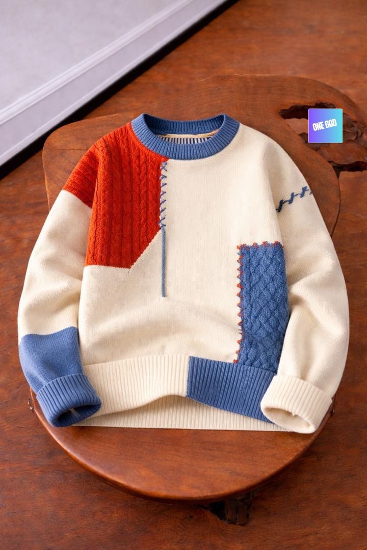 Colorblock cream sweater with red shoulder, blue panels and cable knit textures.